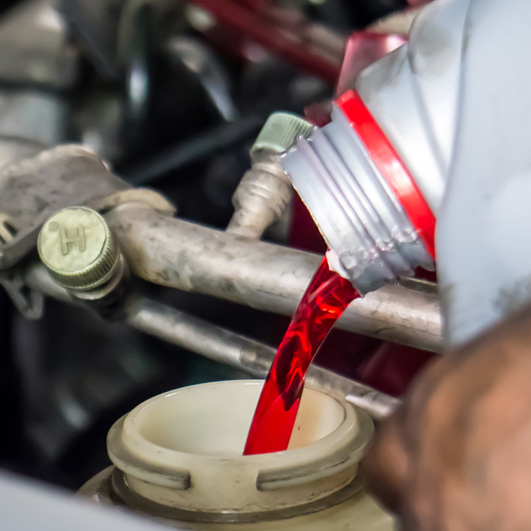 Image of a technician pouring transmission fluid into a car